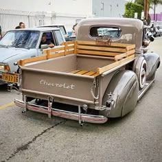 an old pickup truck is parked on the side of the road with other antique cars