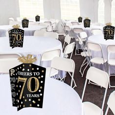 a room filled with tables and chairs covered in white tablecloths topped with black and gold decorations