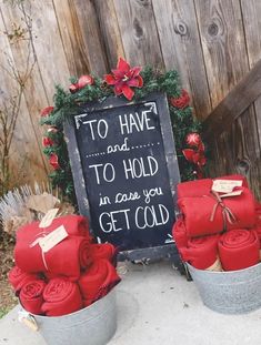 two buckets filled with red roses next to a chalkboard sign that says, to have and to hold in case you get cold