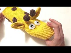 someone is holding up a knitted giraffe mitt with googly eyes