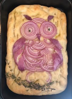 an owl made out of onion and meat in a baking pan with herbs on the side