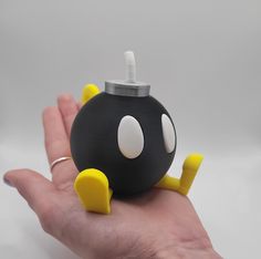 a hand holding a black and yellow object with white dots on it's face