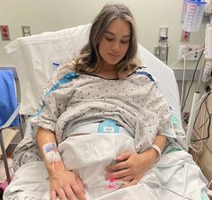 a woman laying in a hospital bed with an iv