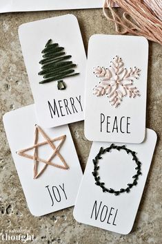 four christmas cards with words on them and some decorations hanging from the top, along with twine