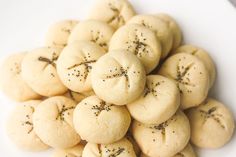 a white plate topped with small cookies covered in black sprinkles