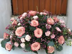 a bouquet of pink flowers sitting on top of a white bench next to a wooden door