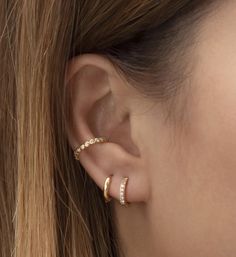 a close up of a woman's ear with two gold rings