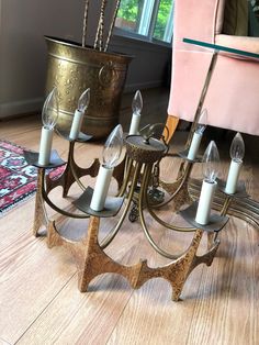 a metal candelabra with candles on it in front of a pink chair