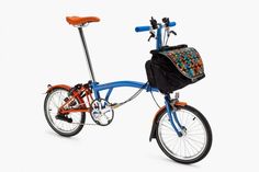 an orange and blue bike with a back pack on it's front wheel, against a white background