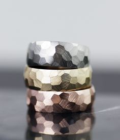 two gold and silver rings sitting on top of each other, one with a diamond pattern