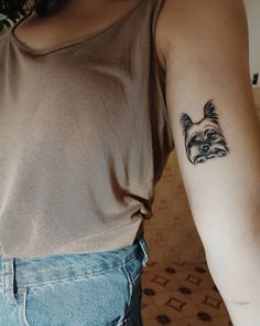 a woman with a small dog tattoo on her arm