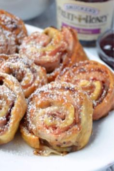 cinnamon rolls on a white plate with powdered sugar and jelly in the background,