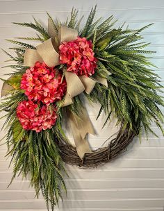 a wreath with pink flowers and greenery hangs on a wall next to a door