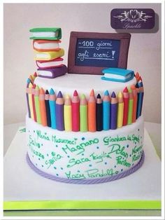 there is a cake that has many colored crayons on it and a chalkboard in the background