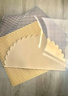 three placemats with scalloped edges on a wooden surface, one in yellow and the other in black