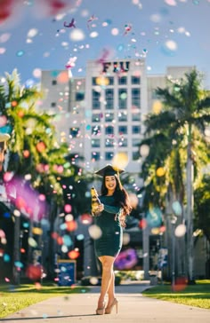 a woman in a green dress and black hat is standing on the sidewalk with bubbles