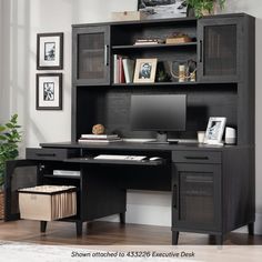 a black computer desk sitting in front of a book shelf