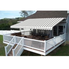 an awning on top of a deck in front of a house with white railings