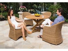 a man and woman sitting at a table with bananas on top of it in wicker chairs