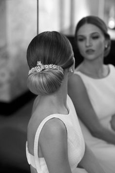 a woman in a white dress is sitting next to another woman wearing a tiara