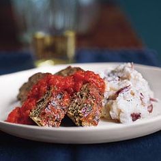 a white plate topped with meatballs and mashed potatoes next to a glass of beer