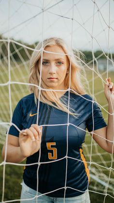 a woman is posing behind a soccer net