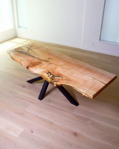 a wooden table sitting on top of a hard wood floor next to a window in an empty room