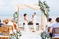 a bride and groom standing at the end of their wedding ceremony in front of the ocean