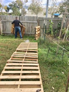 a man standing next to a wooden pallet on top of a lush green field