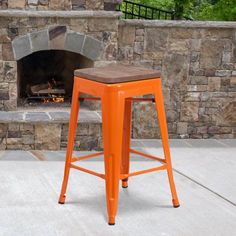 an orange stool sitting in front of a fire place