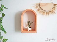 a wooden shelf with a plant in it next to a wall mounted sunburst