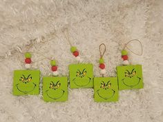 four green tags with faces drawn on them sitting on a white furnishing area