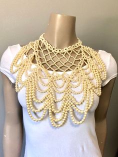 "Pretty faux pearl necklace with all over beads to dress up any look. Beads create a cross cross and drape loop design down the front. Adjustable clasp and chain in gold toned and variety of size beads Measurements: Bib front is 10\" long by 10\" to 5\" wide from top to bottom" Gold Beaded Pearl Necklace For Evening, Elegant Gold Beaded Necklaces For Evening, Beaded Pearl Necklaces For Party, Pearl Beaded Necklaces For Party, Beaded Pearl Necklace For Party, Elegant Bib Necklace With Beaded Chain, Elegant Cream Beaded Necklaces With Pearl Drop, Elegant Cream Beaded Necklaces With Pearl Chain, Costume Jewelry Pearl Beaded Necklaces For Party