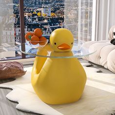 a yellow rubber duck sitting on top of a glass table in front of a window