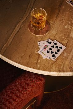 a table with playing cards and a drink on it