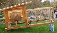 two people are standing in the grass with a chicken coop on it's back