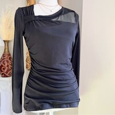 a mannequin wearing a black top with sheer shoulders