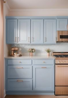 a kitchen with blue cabinets and gold accents on the stove top, oven, microwave and dishwasher