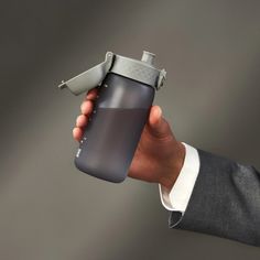 a hand holding a water bottle in the palm of it's left hand, while wearing a suit and tie