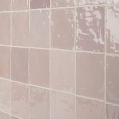 a white toilet sitting next to a pink tiled wall