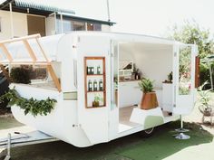 an old trailer converted into a house with plants growing out of the windows and doors