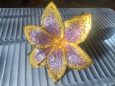 a yellow and purple flower sitting on top of a table