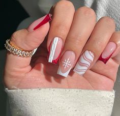 a woman's hand with some red and white nail polishes on her nails