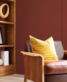 a brown leather chair sitting in front of a wooden book shelf with books on it