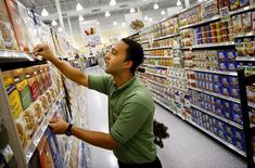 a man in a grocery store picking out food from the shelf and looking at it