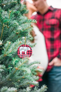 a pregnant couple standing next to a christmas tree with their belly wrapped around the baby bump