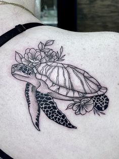 a woman's back with a turtle and flowers on it