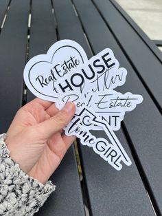 someone holding up some stickers that say real estate house on the side of a bench