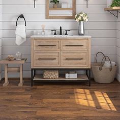 a bathroom with white walls and wood flooring, two mirrors on the wall above the sink