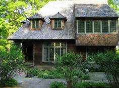 a house in the woods with lots of trees and bushes around it's sides